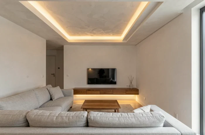 Salon contemporain avec éclairage indirect par bandeaux LED encastrés dans un coffre de plafond et sous un meuble TV flottant