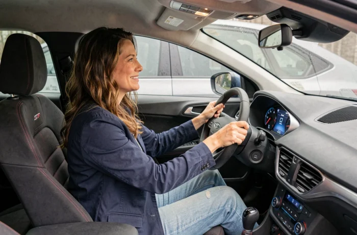 Femme souriante assise dans l'habitacle du Ford Puma ST-Line avec sièges sport et tableau de bord numérique