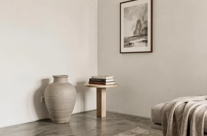 Coin salon épuré avec organisation des volumes privilégiée sur l'accumulation, mettant en valeur un grand vase céramique et quelques livres sélectionnés